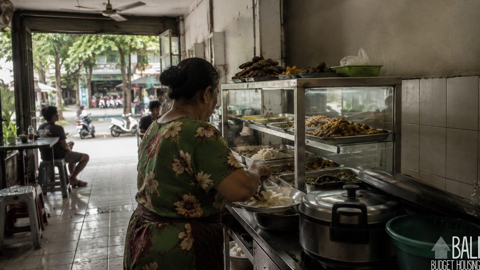 A small family-run warung in Bali serving rice and cooked dishes from display trays